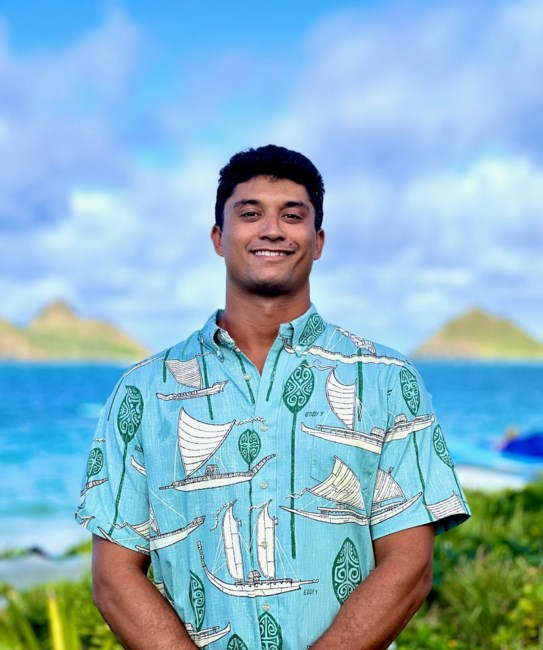 Hopena “Pena” Pokipala standing before Nā Mokulua in a voyaging-canoe print aloha shirt